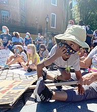 Nelson Foster, 4, participates at the RVA Youth Rally last Saturday with his grandmother, Rita Flowers. The rally drew young people and families to the statue of Maggie L. Walker at Broad and Adams streets in Downtown.