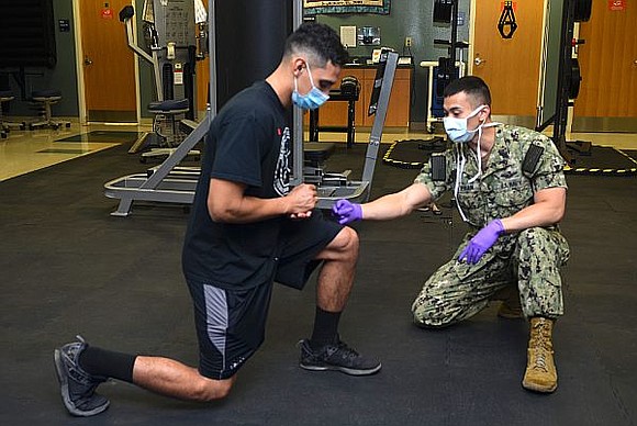 Hospital Corpsman 2nd Class David Phan, from Houston, Texas, helps to rehabilitate Boatswain's Mate 1st Class Leo Torres Teruel, a …