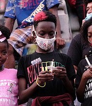 from left, Mymy Hardon, Joel Charles and Amira Jones hold candles during a vigil at the Lee statue to help close out the program at the daylong celebration of the liberation from slavery.