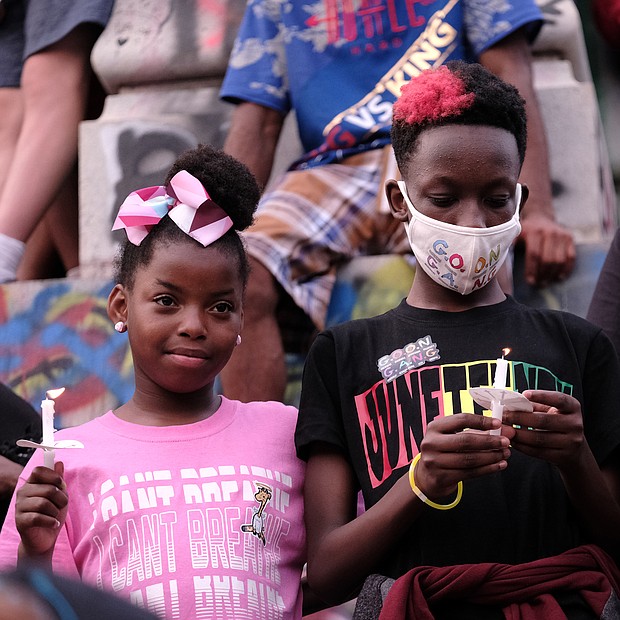 from left, Mymy Hardon, Joel Charles and Amira Jones hold candles during a vigil at the Lee statue to help close out the program at the daylong celebration of the liberation from slavery.