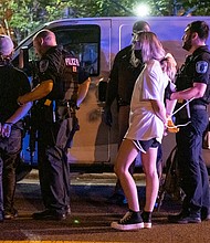 This scene shows two of the six people that police officers arrested for failing to leave the area of the J.E.B. Stuart statue after an unlawful assembly was declared. Ninth District City Councilman Michael J. Jones sought to negotiate with the officers, but police ultimately used tear gas and pepper spray to disperse the crowd.