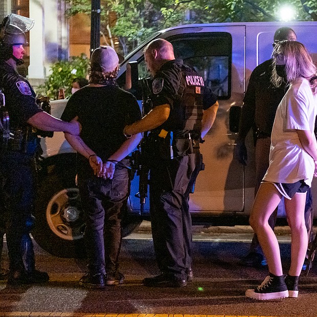 This scene shows two of the six people that police officers arrested for failing to leave the area of the J.E.B. Stuart statue after an unlawful assembly was declared. Ninth District City Councilman Michael J. Jones sought to negotiate with the officers, but police ultimately used tear gas and pepper spray to disperse the crowd.