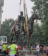 A crane hauls away the massive, 100-year-old statue of Confederate Gen. Thomas “Stonewall” Jackson from its pedestal at Monument Avenue and Arthur Ashe Boulevard during a downpour Wednesday.