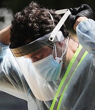 LOS ANGELES, CALIFORNIA  - JULY 07: A COVID-19 testing associate adjusts his personal protective equipment (PPE) at a testing center at Lincoln Park amid the coronavirus pandemic on July 07, 2020 in Los Angeles, California. There has been a spike in new coronavirus cases in California along with an increase in the overall positivity rate and number of hospitalizations. (Photo by Mario Tama/Getty Images)/Credit:	Mario Tama/Getty Images