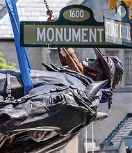 The statue of Confederate Gen. J.E.B. Stuart is turned on its side and lowered onto a flatbed truck Tuesday after being removed from its pedestal at Monument Avenue and Stuart Circle. It is the last of four city-owned statues on the tree-lined street to be taken down and sent to storage.
