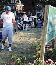 Gary Foley, a regular at the square, waters flowers and tomatoes planted around a sign bearing the circle’s new name given by protesters, Marcus-David Peters Circle, to remember the man killed by a Richmond Police officer in May 2018.
