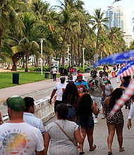 People walk past restaurants on Ocean Drive on July 03, 2020 in the South Beach neighborhood of Miami Beach, Florida. In order to prevent the spread of COVID-19, Miami-Dade county has closed beaches from July 3-7 and imposed a curfew from from 10pm to 6am./Credit:	Cliff Hawkins/Getty Images