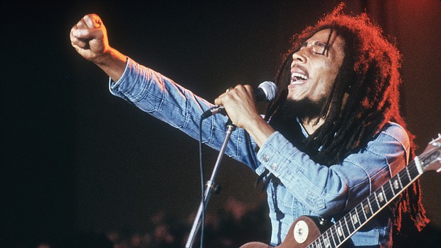 Jamaican Reggae musician, songwriter, and singer Bob Marley performs on stage, in a concert at Grona Lund, Stockholm, Sweden. He extends his fist as he sings into the microphone, with an electric guitar./Credit:	Hulton Archive/Archive Photos/Getty Images