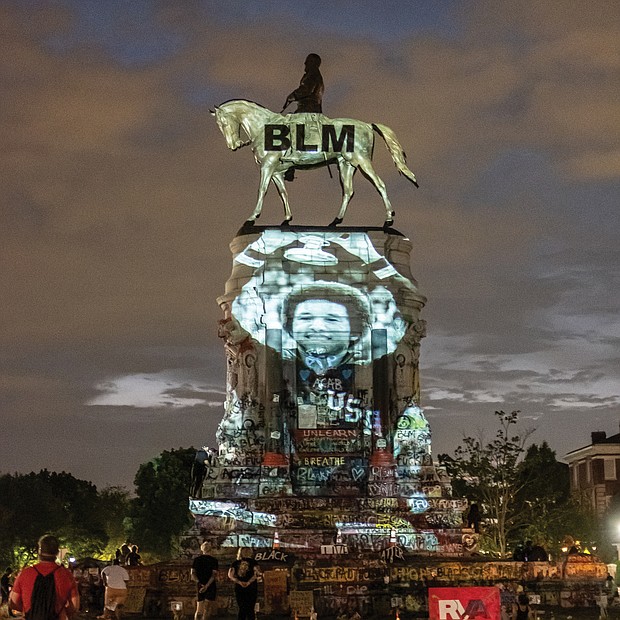 On Friday evening, local artist Dustin Klein projects on the base of the Lee statue an image of Richmond hometown hero Arthur Ashe Jr. in honor of the tennis great’s birthday on July 10. The photo shows Mr. Ashe holding up the championship trophy after his historic win in the men’s singles competition at Wimbledon on July 5, 1975.