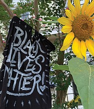 From hand-held signs to spray paint on statue pedestals and banners, the proclamation that Black Lives Matter, or BLM, is visible across the city. Here, a sunflower adds a splash of color to a supportive homemade flag flying in front of a home in The Fan. Location: Kensington Avenue.