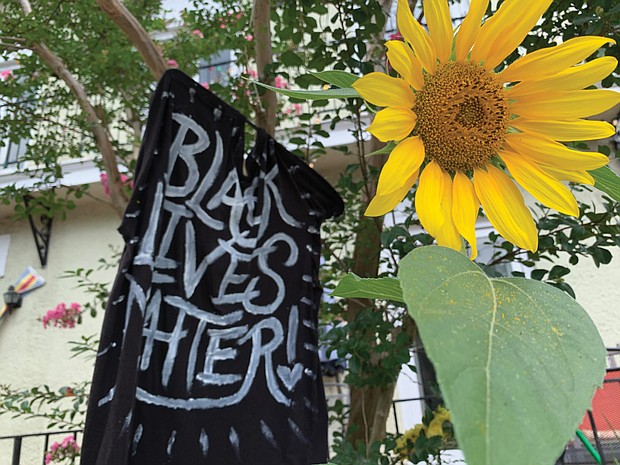 From hand-held signs to spray paint on statue pedestals and banners, the proclamation that Black Lives Matter, or BLM, is visible across the city. Here, a sunflower adds a splash of color to a supportive homemade flag flying in front of a home in The Fan. Location: Kensington Avenue.