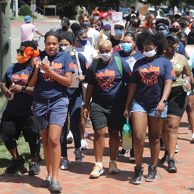 Lux Aghomo, 17, front, uses a small bullhorn to start the chants during RISE For Youth’s “Extra Mile for Justice Parade” last Saturday at Monroe Park to benefit the organization’s inaugural youth development academy to start next year.