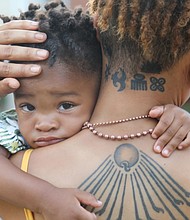 Akenji Joseph, 2, clings to his mother, Kamala Bhagat, as the two joined a socially distanced crowd of about 100 people last Sunday for the final porch concert of Plunky & Oneness in the city’s West End.