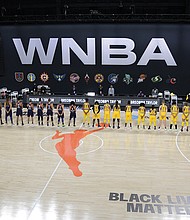 Members of the Phoenix Mercury, in blue, and the Los Angeles Sparks stand for a moment of silence in honor of Breonna Taylor before a WNBA basketball game last Saturday in Ellenton, Fla.