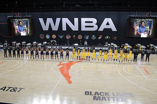 Members of the Phoenix Mercury, in blue, and the Los Angeles Sparks stand for a moment of silence in honor of Breonna Taylor before a WNBA basketball game last Saturday in Ellenton, Fla.