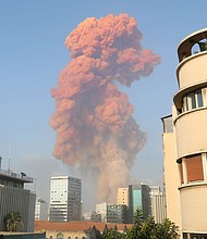 A red cloud hangs over Beirut in the wake of an explosion at the port. The source of the explosion was a major fire at a warehouse for firecrackers near the port in Beirut, the state-run National News Agency reported./Credit:	ANWAR AMRO/AFP/Getty Images