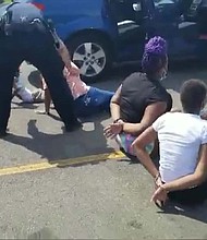 A Facebook video shows the children on the ground in a parking lot, surrounded by police./Credit:	Jenni Bennet/Facebook