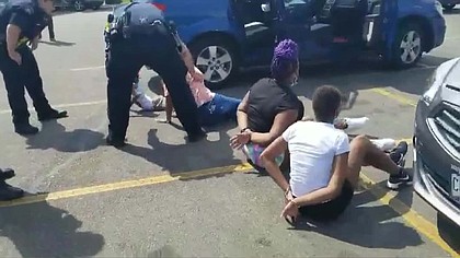 A Facebook video shows the children on the ground in a parking lot, surrounded by police./Credit:	Jenni Bennet/Facebook