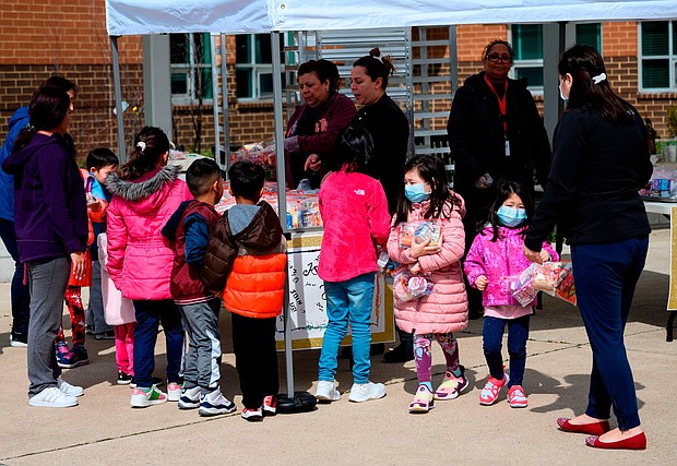 Children, some wearing face masks as a preventive measure, pick up free lunch at Kenmore Middle School in Arlington, Virginia on March 16, 2020, after schools in the area closed due to the coronavirus outbreak./Credit:	Andrew Caballero-Reynolds/AFP/Getty Images