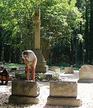 Dr. Johnny Mickens III, right, the great-grandson of Maggie L. Walker, and his daughter, Liza Mickens, survey the damage Monday morning at Mrs. Walker’s gravesite in historic Evergreen Cemetery. The back of the headstone, entrances to the gravesite and benches around the gravesite were spraypainted with “777,” numbers that are linked to white supremacist groups.