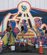 New murals are sprouting as artists seek to lend their vision to the Black Lives Matter movement. Here, Chris Visions, left, and Emily Herr portray their view of the world on a building in the 2900 block of West Marshall Street in Scott’s Addition. This work is one of three murals adoring the building and was commissioned by the building’s owner.