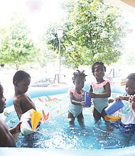 Mom Ajibola Taiwo tries to keep from getting wet during splash time with her 3-year-old sextuplets on a recent hot summer afternoon. the youngsters are, from left, Jubeelo, sindara, Funbi, Semiloore, Setemi and Morayo. Mrs. Taiwo said it takes teamwork with her husband, Adeboye taiwo, to make their household in the Fan run smoothly. the Taiwos are natives of Nigeria.
