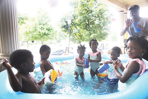 Mom Ajibola Taiwo tries to keep from getting wet during splash time with her 3-year-old sextuplets on a recent hot summer afternoon. the youngsters are, from left, Jubeelo, sindara, Funbi, Semiloore, Setemi and Morayo. Mrs. Taiwo said it takes teamwork with her husband, Adeboye taiwo, to make their household in the Fan run smoothly. the Taiwos are natives of Nigeria.