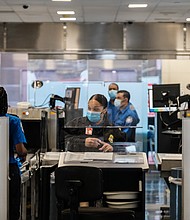 TSA agents work at a security checkpoint at the Ronald Reagan National Airport on July 22, 2020 in Arlington, Virginia. During the COVID-19 pandemic, all employees and passengers are required to wear facemasks while onboard a Delta plane./Credit:	Michael A. McCoy/Getty Images North America/Getty Images