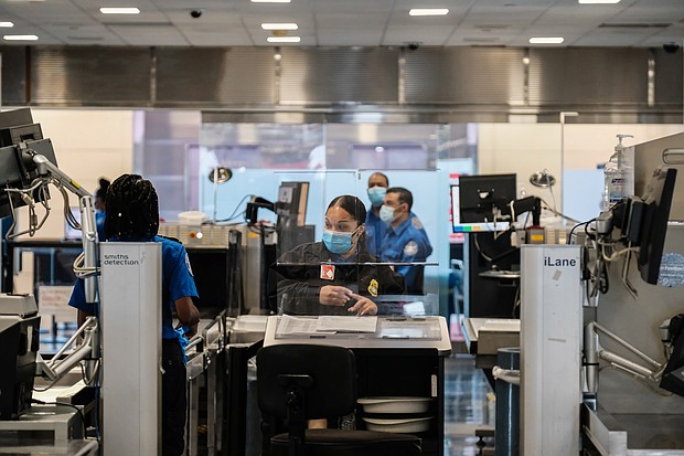 TSA agents work at a security checkpoint at the Ronald Reagan National Airport on July 22, 2020 in Arlington, Virginia. During the COVID-19 pandemic, all employees and passengers are required to wear facemasks while onboard a Delta plane./Credit:	Michael A. McCoy/Getty Images North America/Getty Images