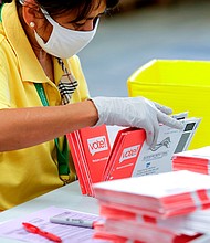 An election worker opens envelopes containing vote-by-mail ballots for the August 4 Washington state primary at King County Elections in Renton, Washington on August 3, 2020.A sign explaining signature verification is pictured as vote-by-mail ballots for the August 4 Washington state primary are processed at King County Elections in Renton, Washington on August 3, 2020./Credit:	Jason Redman/AFP/Getty Images
