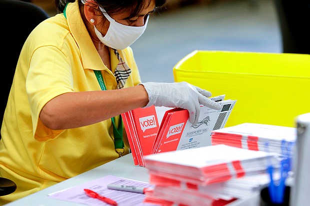 An election worker opens envelopes containing vote-by-mail ballots for the August 4 Washington state primary at King County Elections in Renton, Washington on August 3, 2020.A sign explaining signature verification is pictured as vote-by-mail ballots for the August 4 Washington state primary are processed at King County Elections in Renton, Washington on August 3, 2020./Credit:	Jason Redman/AFP/Getty Images