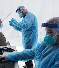 St. John's Well Child & Family Center workers prepare to test a woman for COVID-19 at a free mobile test clinic set up outside Walker Temple AME Church in South Los Angeles amid the coronavirus pandemic on July 15, 2020 in Los Angeles, California./Credit:	Mario Tama/Getty Images