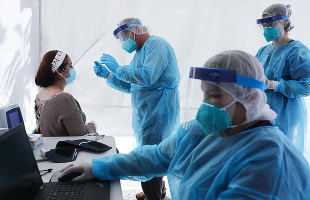 St. John's Well Child & Family Center workers prepare to test a woman for COVID-19 at a free mobile test clinic set up outside Walker Temple AME Church in South Los Angeles amid the coronavirus pandemic on July 15, 2020 in Los Angeles, California./Credit:	Mario Tama/Getty Images
