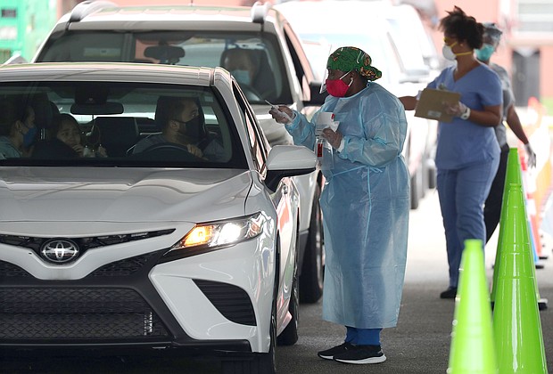 A health care worker directs a person to use a nasal swab for a self administered test at the new federally funded COVID-19 testing site at the Miami-Dade County Auditorium on July 23, 2020 in Miami, Florida. Vice Admiral Jerome Adams, the U.S. Surgeon General, visited the site, as the state of Florida experiences a spike in coronavirus cases, to encourage people to wear a mask and take other precautions to fight the pandemic./Credit:	Joe Raedle/Getty Images