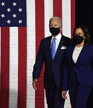 A masked Joe Biden and Kamala Harris walk to the stage where they will make their first appearance on the Democratic ticket together./Credit:	Olivier Douliery/AFP/Getty Images