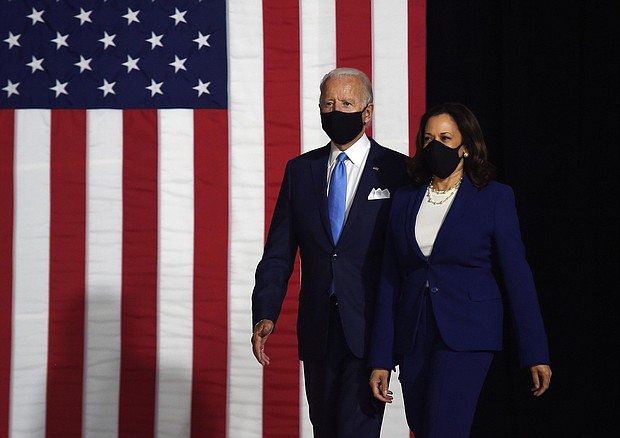 A masked Joe Biden and Kamala Harris walk to the stage where they will make their first appearance on the Democratic ticket together./Credit:	Olivier Douliery/AFP/Getty Images