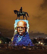 A picture of the late Congressman John Lewis of Georgia, a lion of the Civil Rights Movement, is projected onto the pedestal of Confederate Gen. Robert E. Lee’s statue on Monument Avenue, reclaiming the space for the history and triumphs of African-Americans. the projection was done after Rep. Lewis’ death on July 17.