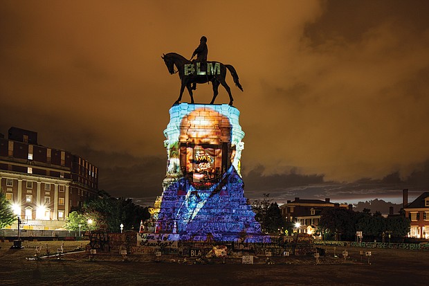 A picture of the late Congressman John Lewis of Georgia, a lion of the Civil Rights Movement, is projected onto the pedestal of Confederate Gen. Robert E. Lee’s statue on Monument Avenue, reclaiming the space for the history and triumphs of African-Americans. the projection was done after Rep. Lewis’ death on July 17.