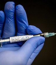 In the Institute of Tropical Medicine at the University Hospital in Tübingen, a man is holding a syringe with which a young woman, the first test person, was injected with a potential active substance against the corona virus./Credit:	Christoph Schmidt/picture alliance/Getty Images