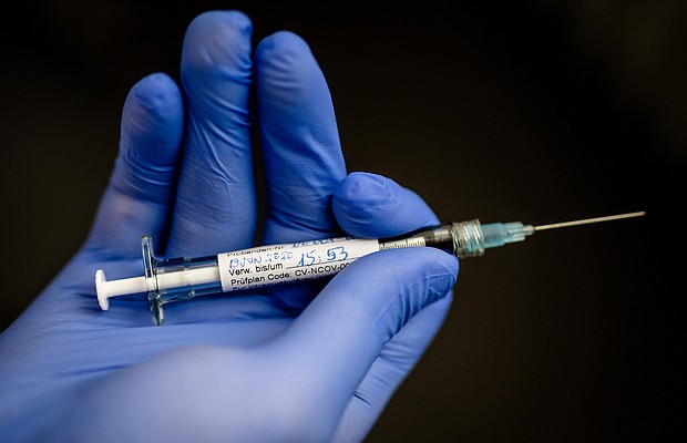 In the Institute of Tropical Medicine at the University Hospital in Tübingen, a man is holding a syringe with which a young woman, the first test person, was injected with a potential active substance against the corona virus./Credit:	Christoph Schmidt/picture alliance/Getty Images