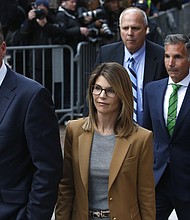 Lori Loughlin, in tan at center, leaves as her husband Mossimo Giannulli, in green tie at right, follows behind her outside the John Joseph Moakley United States Courthouse in Boston on April 3, 2019. Hollywood stars Felicity Huffman and Lori Loughlin were among 13 parents scheduled to appear in federal court in Boston Wednesday for the first time since they were charged last month in a massive college admissions cheating scandal. They were among 50 people - including coaches, powerful financiers, and entrepreneurs - charged in a brazen plot in which wealthy parents allegedly schemed to bribe sports coaches at top colleges to admit their children. Many of the parents allegedly paid to have someone else take the SAT or ACT exams for their children or correct their answers, guaranteeing them high scores. (Photo by Jessica Rinaldi/The Boston Globe via Getty Images)/Credit:	Boston Globe/Boston Globe/Boston Globe via Getty Images