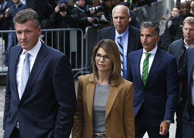 Lori Loughlin, in tan at center, leaves as her husband Mossimo Giannulli, in green tie at right, follows behind her outside the John Joseph Moakley United States Courthouse in Boston on April 3, 2019. Hollywood stars Felicity Huffman and Lori Loughlin were among 13 parents scheduled to appear in federal court in Boston Wednesday for the first time since they were charged last month in a massive college admissions cheating scandal. They were among 50 people - including coaches, powerful financiers, and entrepreneurs - charged in a brazen plot in which wealthy parents allegedly schemed to bribe sports coaches at top colleges to admit their children. Many of the parents allegedly paid to have someone else take the SAT or ACT exams for their children or correct their answers, guaranteeing them high scores. (Photo by Jessica Rinaldi/The Boston Globe via Getty Images)/Credit:	Boston Globe/Boston Globe/Boston Globe via Getty Images