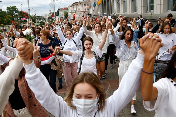 Gathered just outside the barbed wire fence, a group of protesters young and old raised their voices in song. Accompanied …