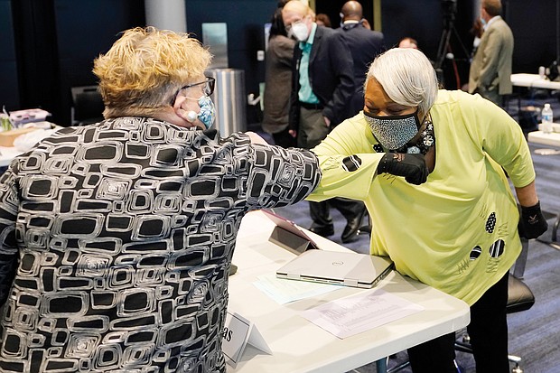 State Sen. Louise Lucas of Portsmouth, right, gives Senate Clerk Susan Schaar an elbow bump during a break tuesday during the first day of the General Assembly’s special session in Richmond. Because of the pandemic, the Senate is holding its sessions at the Science Museum of Virginia.