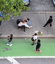 People sit on a traffic island in Kips Bay as the city continues Phase 4 of re-opening following restrictions imposed to slow the spread of coronavirus on August 17, 2020 in New York City./Credit: Noam Galai/Getty Images