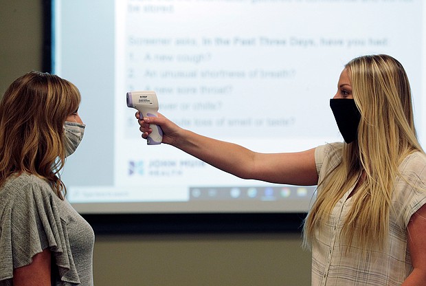 Vickie Moul, director of HR at Armanino at Bishop Ranch, has her temperature checked by administrative assistant Taylor MIlls during a training session for employees to screen office workers for Covid-19 symptoms at the company's offices in San Ramon, California, on June 16, 2020./Credit: Carlos Avila Gonzalez/The San Francisco Chronicle/Getty Images)