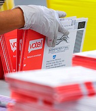 An election worker opens envelopes containing vote-by-mail ballots for the August 4 Washington state primary at King County Elections in Renton, Washington./Credit:	JASON REDMOND/AFP/Getty Images