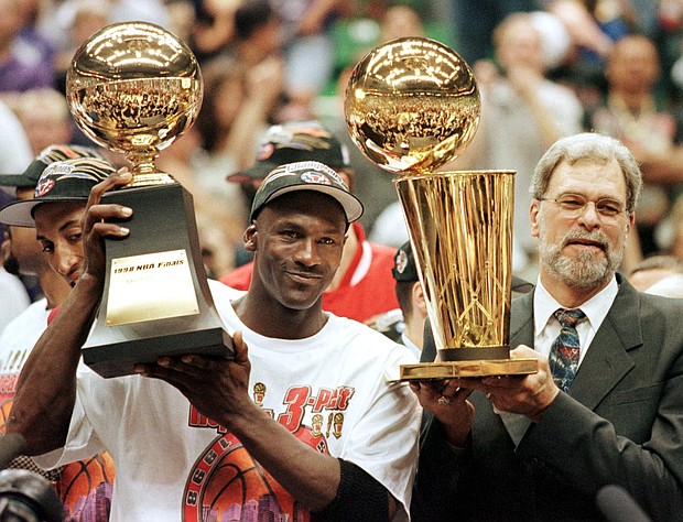 Michael Jordan (L) and Chicago Bulls head coach Phil Jackson after the Bulls won their sixth NBA championship./Credit:	JEFF HAYNES/AFP/AFP via Getty Images