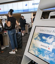 Travelers wearing protective masks use kiosks to check-in at the American Airlines Group Inc. counter at San Francisco International Airport in San Francisco, California on Wednesday, July 1, 2020./Credit:	David Paul Morris/Bloomberg/Getty Images
