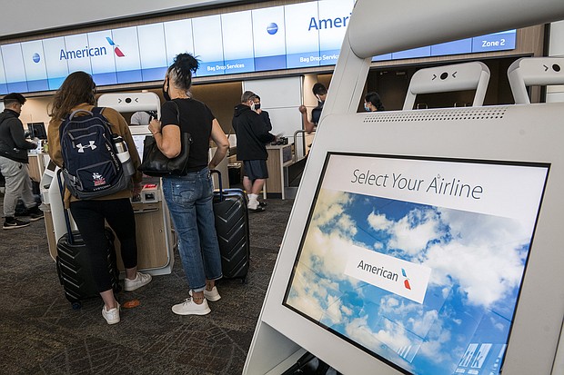 Travelers wearing protective masks use kiosks to check-in at the American Airlines Group Inc. counter at San Francisco International Airport in San Francisco, California on Wednesday, July 1, 2020./Credit:	David Paul Morris/Bloomberg/Getty Images